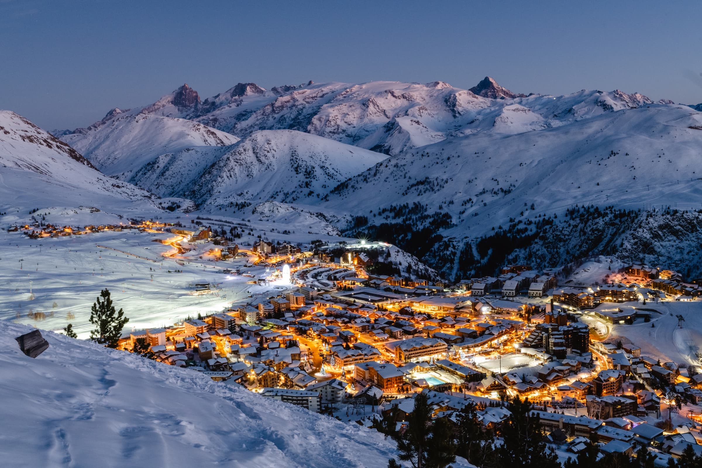 Station enneigée illuminée au crépuscule dans l’Oisans